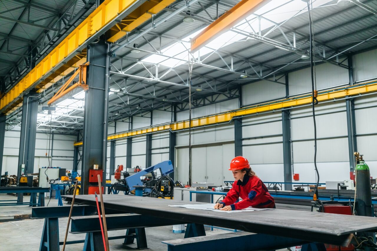 People working in a manufacturing warehouse with blueprints